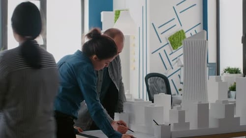 Team of Architects Planning Design with Blueprints and Building Model on Table