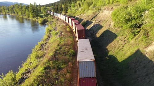 Aerial view of freight train passing by a river