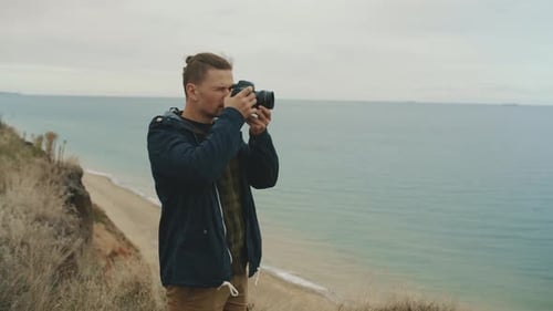 A Young Photographer on the Seashore Takes a Seascape on Camera