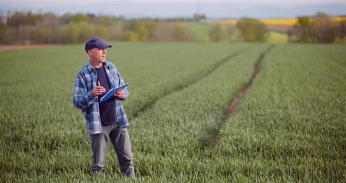 Thoughtful Male Botanist Writing On Clipboard. Farmer Examining Agriculture Field.