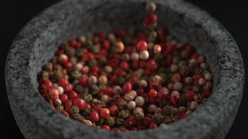 Peppercorns Falling into Stone Mortar Bowl