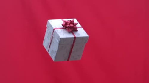 Christmas present tossed into the air on red background