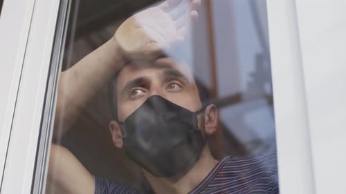 Homem com máscara protetora atrás da janela em quarentena