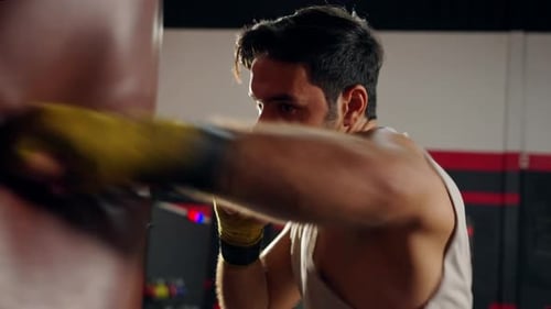 4K Caucasian man athlete do boxing exercise with punching bag at gym