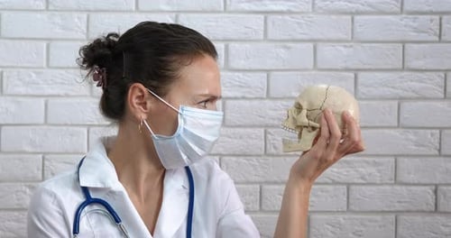 Woman Doctor Holding Skull Wearing Surgical Mask