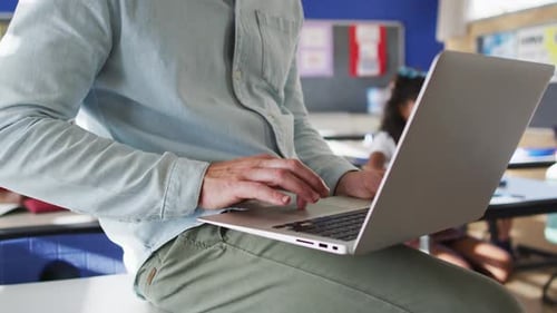 Mittelteil eines kaukasischen Lehrers im Klassenzimmer mit Kindern mit Laptop