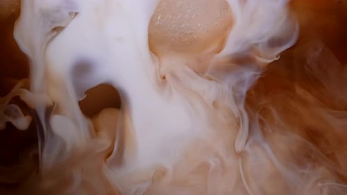 Cream being poured into iced coffee, close up