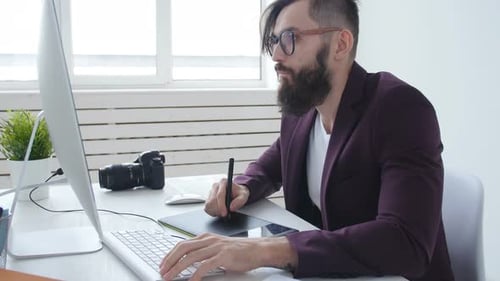 Man with Beard Working at Computer with Tablet