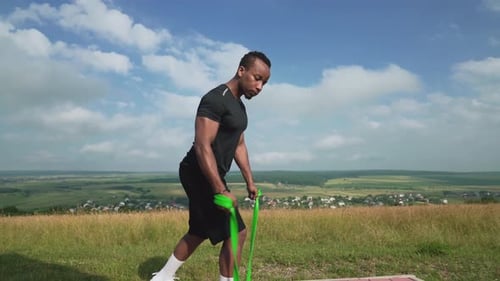 Muscular Adult Man Exercising with Resistance Band Outdoors