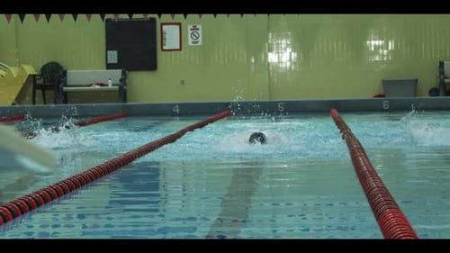 Swimmers Performing Butterfly Stroke in Indoor Pool