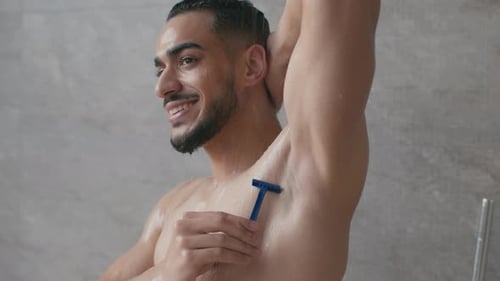 Smiling Man Shaves Underarm in Shower