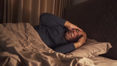 Distressed Man Lying Awake at Night in Bed