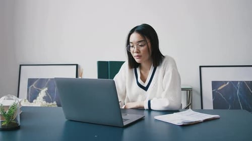 Woman Working at Desk with Laptop and Notes