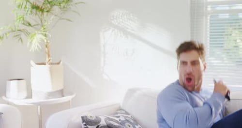 Excited Man Watches Entertainment at Home on Couch
