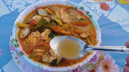 Personne dégustant une belle soupe Tom Yam Kung avec une cuillère.