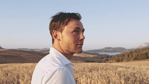 Homem bonito no meio do prado aberto admirando o horizonte em um dia de verão
