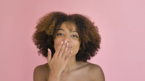Young Woman with Curly Hair Blowing a Kiss