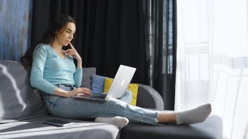Woman Using Laptop for Video Call on Sofa
