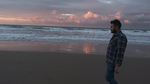Man Walking on Beach at Sunset