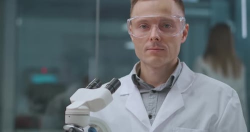 Serious Scientist with Microscope in Modern Lab