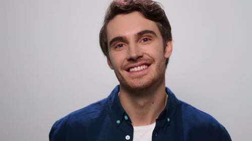 Mann lächelt in die Kamera auf weißem Hintergrund, Positiver Kerl steht im Studio