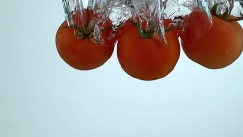 Fresh Tomatoes Plunging into Water with Bubbles