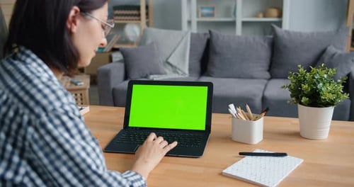 Slow Motion of Person Using Laptop Computer with Green Mock-up Screen at Home