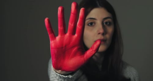 Trauriges Mädchen hebt ihre Hand rot gemalt, um zu stoppen und gegen Gewalt zu protestieren