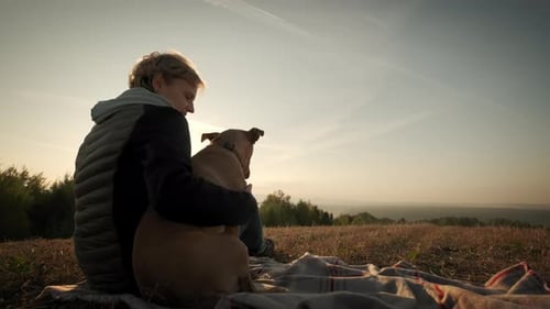 Woman and Dog Enjoying Sunset in Grassy Field