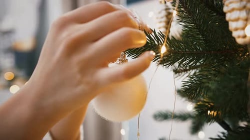 Woman Decorates Christmas Tree with Ornament