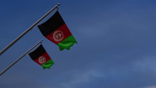 Two Afghanistan Flags Waving on Poles against a Blue Sky