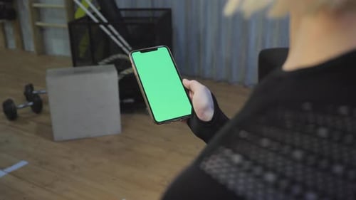 A Young Athletic Woman Holds A Smartphone in Her Hand, Shows A Green Chromakey Screen