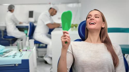 Woman Smiles, Admiring Teeth in Dentist Clinic
