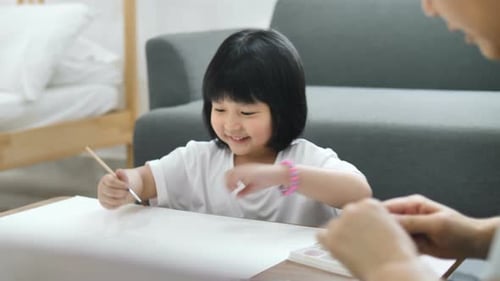 Little Girl Painting with an Adult Indoors