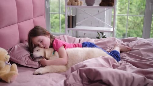 Girl Cuddles with Cream Colored Dog on Pink Bed