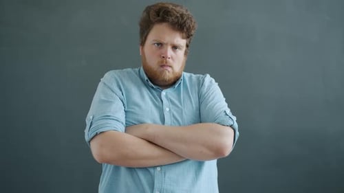 Slow Motion Portrait of Aggressive Young Man Crossing Arms and Looking at Camera with Angry Face