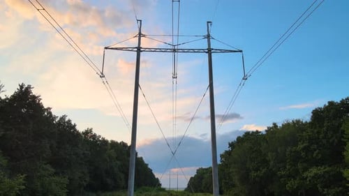Dark Silhouette of High Voltage Tower with Electric Power Lines at Sunset