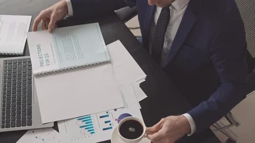 Adult Reviews Projections with Coffee and Laptop