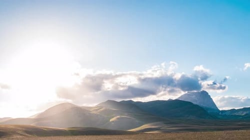 Zeitraffer: Wolken bewegen sich am Himmel, Aussichtspunkt des Sonnenuntergangs über felsige Berge, Hochland und Weiden