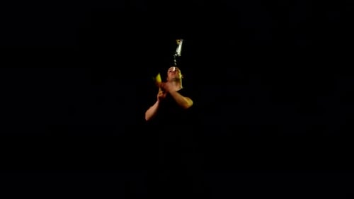 Man Juggling Three Objects on Black Background