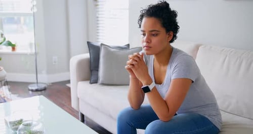 Woman Sitting Thoughtfully on Sofa in Bright Home
