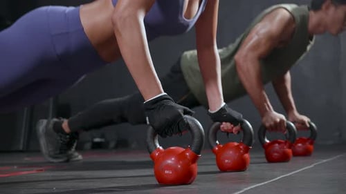 Sporty young couple doing push-ups on weights at gym. fitness, sports concept.