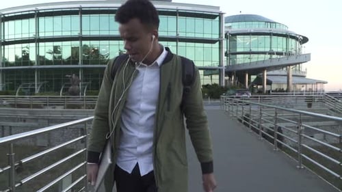 Man Walking With Laptop on City Bridge