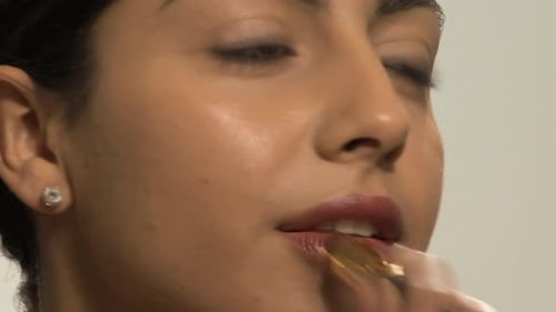 CU OF A YOUNG WOMAN APPLYING LIPSTICK