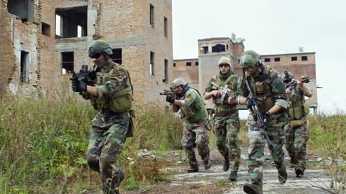 Soldiers in Camouflage Advance Through Ruins With Rifles