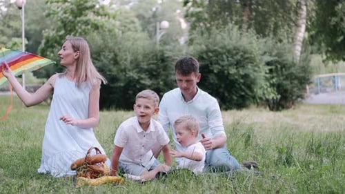 Parents and Two Sons Are Sitting on the Grass in the Park