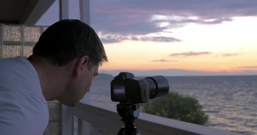 Man Shooting Timelapse of Sunset Over the Sea