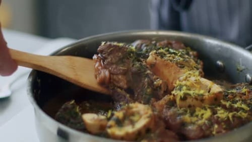 Woman serving delicious ossobuco on ceramic plate