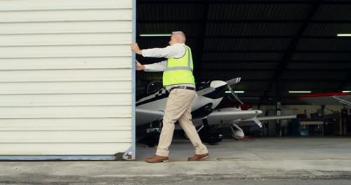 Ingeniero hombre abriendo persiana de hangar