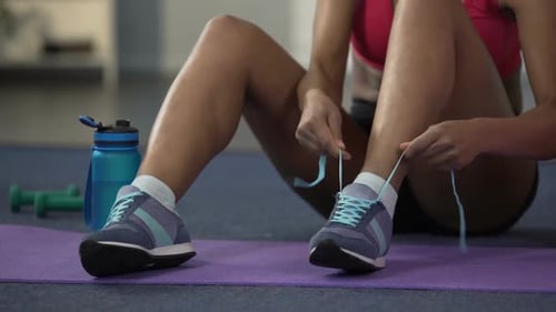 Woman Tying Shoelaces After Workout at Home